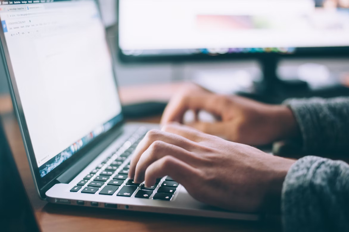 a person writing on keyboard using his laptop